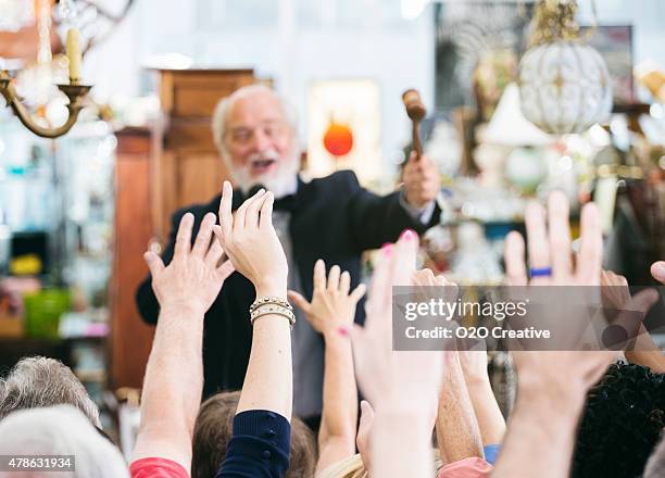 auctioneer with large crowd of buyers - man in antique shop stock pictures, royalty-free photos & images