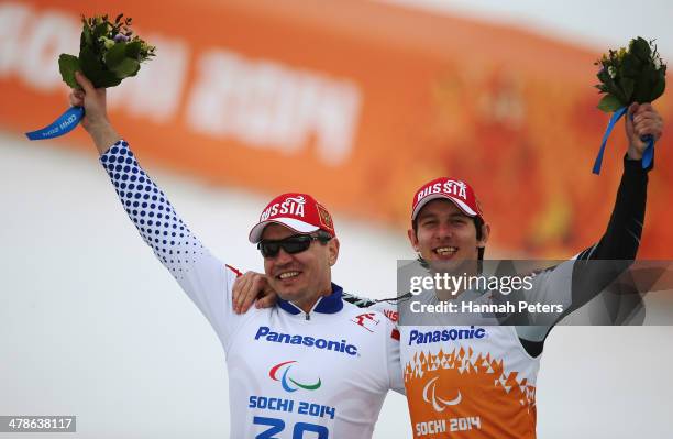 Gold medalist Valerii Redkozubov of Russia with his guide Evgeny Geroev celebrate during the flower ceremony for the Men's Super Combined Visually...