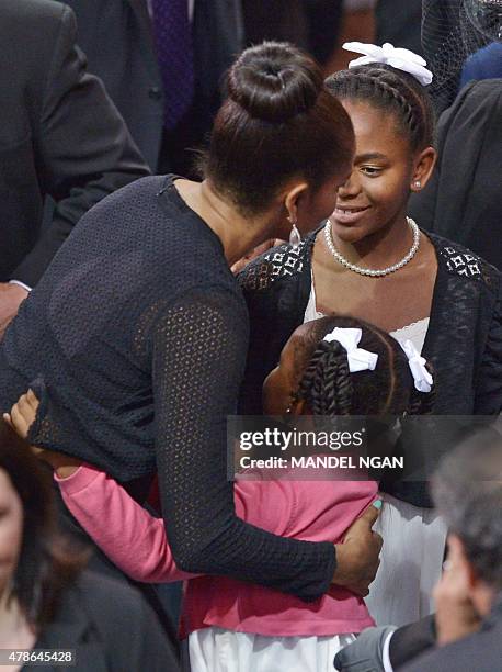 First Lady Michelle Obama hugs Malana Pinckney , the daughter of the slain Rev. And South Carolina State Sen. Clementa Pinckney, while speaking to...