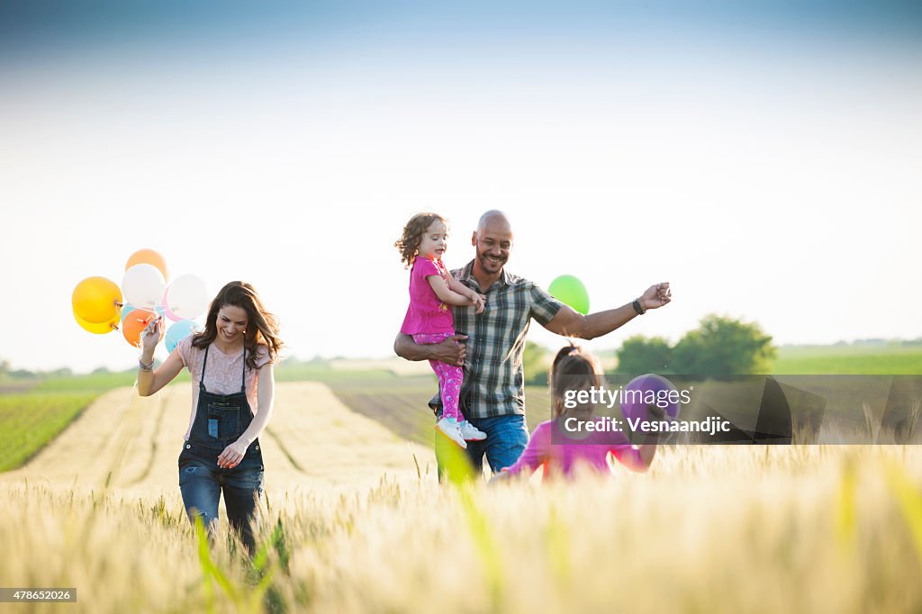 Beautiful multi ethnic family running through wheat field
