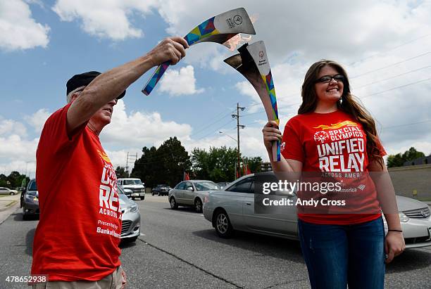 Jorden Marklowitz, right, transfers the Special Olympics Flame of Hope to Don Roth, left, for the Special Olympics Unified Relay Across America along...
