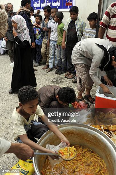 Yemenis wait in line at a school garden in Sumeyla district of capital Sanaa to receive food aids provided by the union of non-governmental...