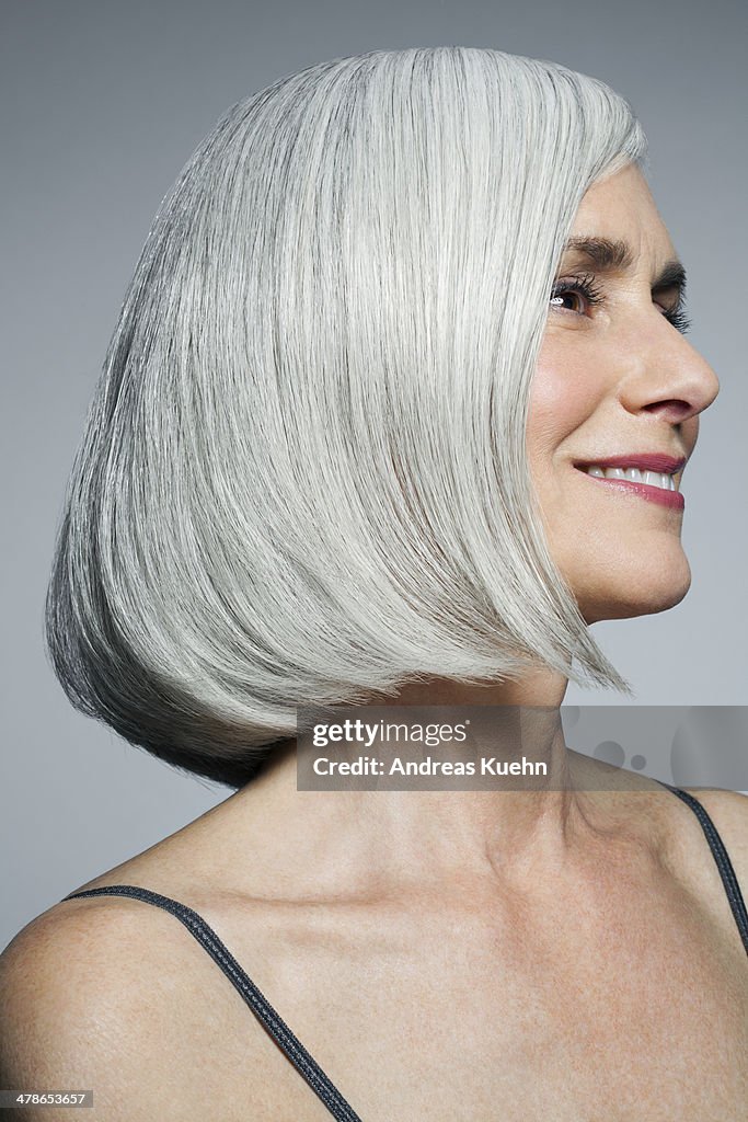 Grey haired woman looking off camera, smiling.