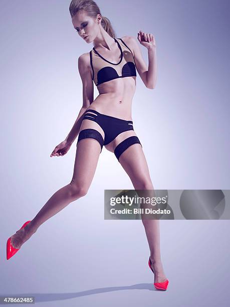 woman in swimsuit and heels jumping - slank stockfoto's en -beelden