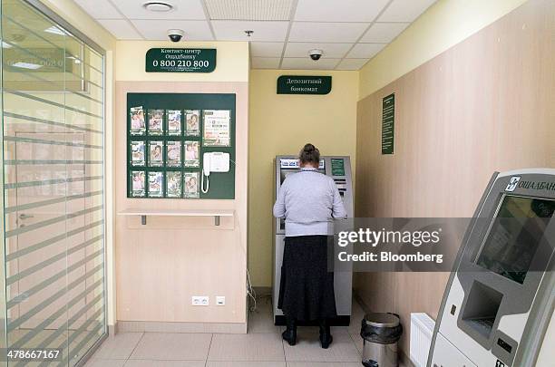 Customer uses an automated teller machine inside an Oschabank bank branch in Kiev, Ukraine, on Friday, March 14, 2014. Ukraine's Eurobonds weakened...