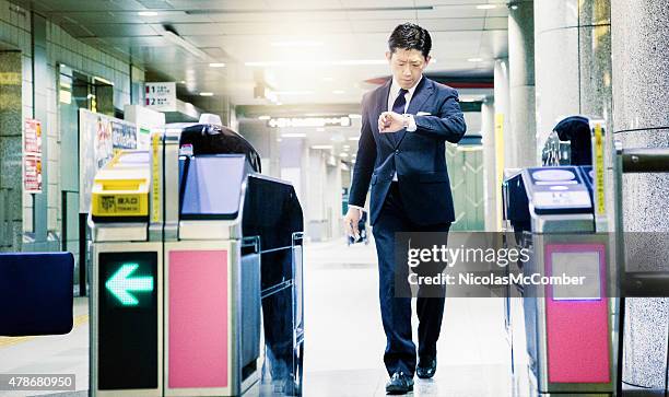 japanese businessman in a hurry exits subway looking at watch - japan commuters stock pictures, royalty-free photos & images