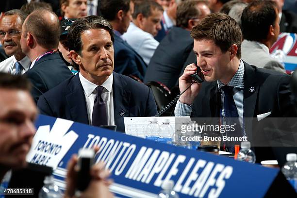 Kyle Dubas Assistant General Manager of the Toronto Maple Leafs talks on the phone as President Brendan Shanahan looks on during the first round of...
