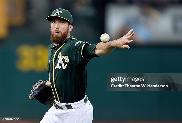 Ike Davis of the Oakland Athletics throws the ball away for an error attempting to get it to pitcher Jesse Hahn covering first base against the...