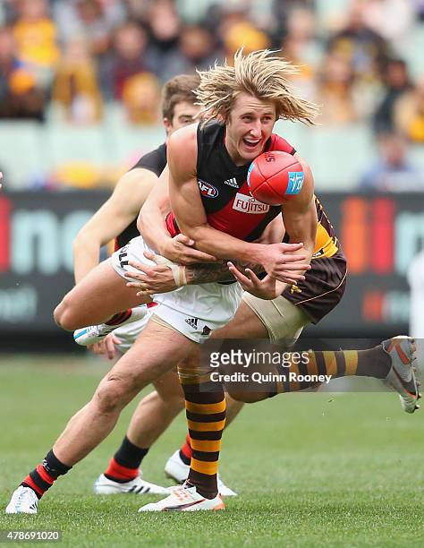 Dyson Heppell of the Bombers handballs whilst being tackled by Shaun Burgoyne of the Hawks during the round 13 AFL match between the Hawthorn Hawks...