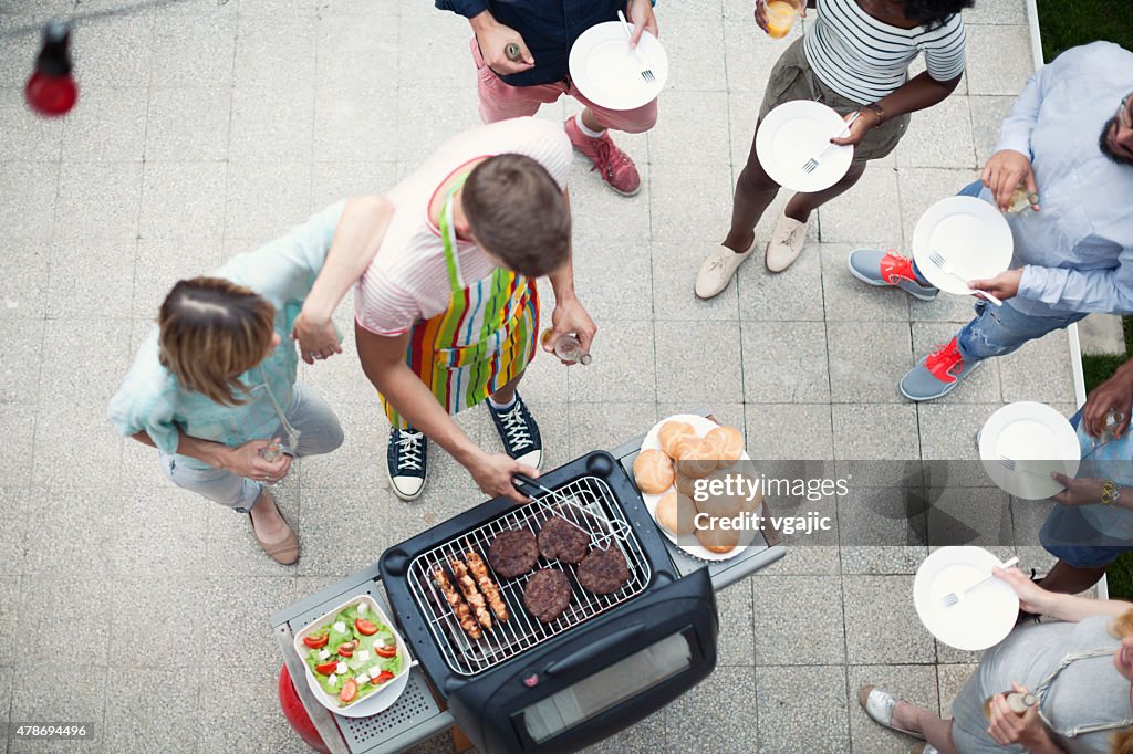 Happy Young People Eating At Barbecue Party.