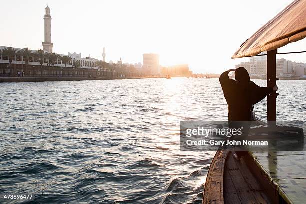 arab woman crossing dubai creek on a boat - dubai people stock pictures, royalty-free photos & images