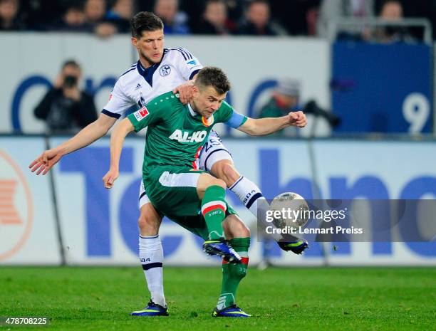 Daniel Baier of Augsburg challenges Klaas-Jan Huntelaar of Schalke during the Bundesliga match between FC Augsburg and FC Schalke 04 at SGL Arena on...