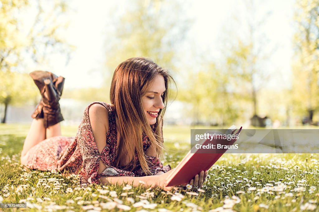 Lächelnde Frau entspannend auf Gras und Lesung Buch.