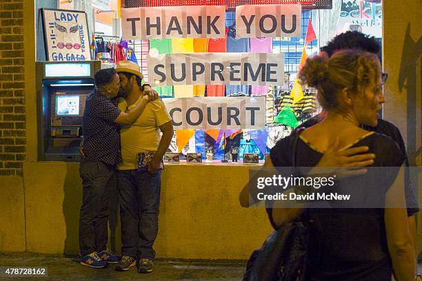 Men kiss near a window display expressing gratitude as people celebrate the Supreme Court ruling on same-sex marriage on June 26, 2015 in West...
