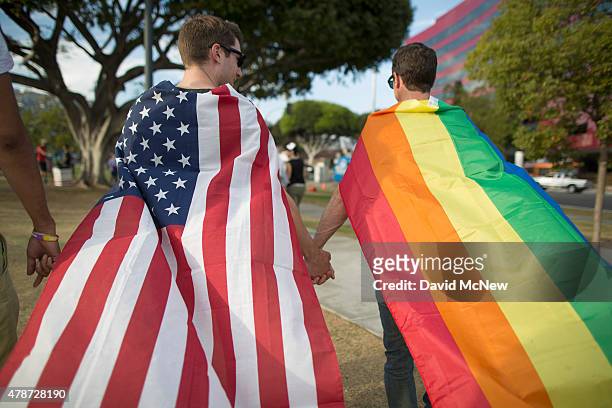 Robert Oliver and Mark Heller hold hands, draped in flags, as they celebrate the Supreme Court ruling on same-sex marriage on June 26, 2015 in West...