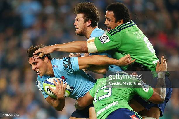 Nick Phipps of the Waratahs is tackled by Malakai Fekitoa and Nasi Manu of the Highlanders with Rob Horne of the Waratahs in support during the Super...