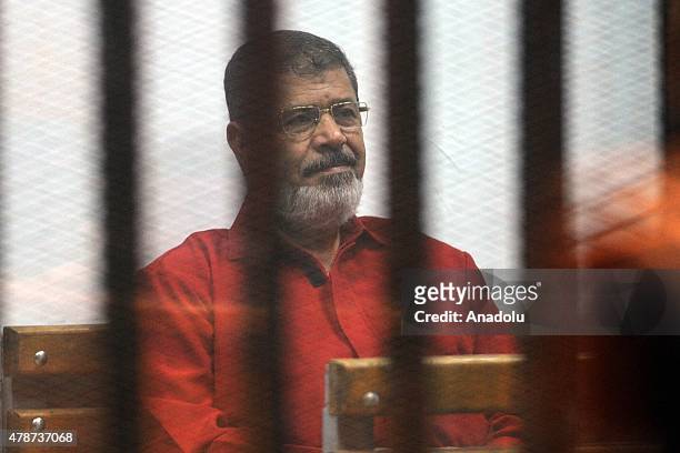 Former Egyptian President Mohamed Morsi, wearing a red uniform after Cairo Criminal Court sentenced him to death over a prison break in 2011, stands...