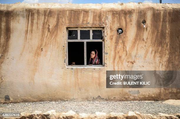 Syrian Kurdish woman sits by the window of a house in Suruc in Turkey's Sanliurfa province near the border with Syria on June 27, 2015. Kurdish...