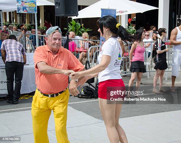 Salsa on St. Saint Clair Festival Scenes: A couple dancing in the street swing around so that the womans ponytail flies behind her. Her partner is a...