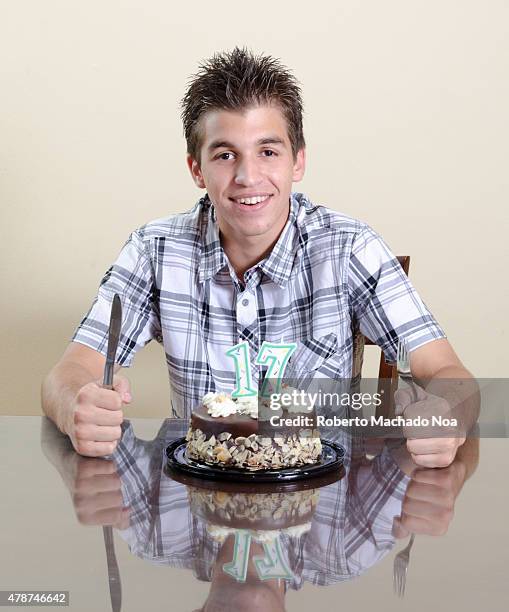 Real birthday celebration: Teenage boy sitting behind a birthday cake with chocolate frosting, decorations, and a number one candle and a number...