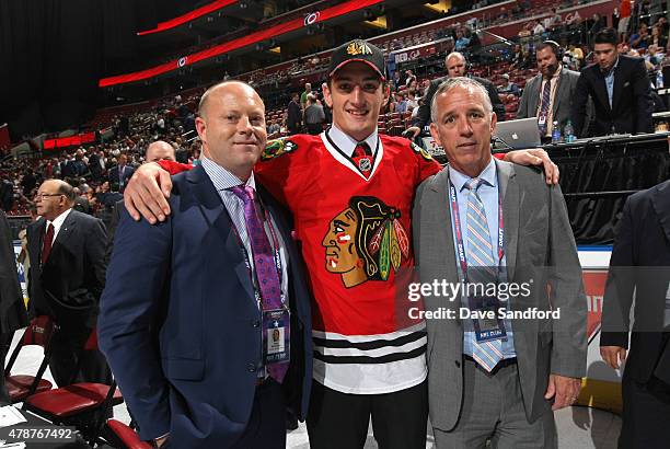 Dennis Gilbert, 91st overall pick of the Chicago Blackhawks, stands on the draft floor with Stan Bowman and Mark Kelley during the 2015 NHL Draft at...