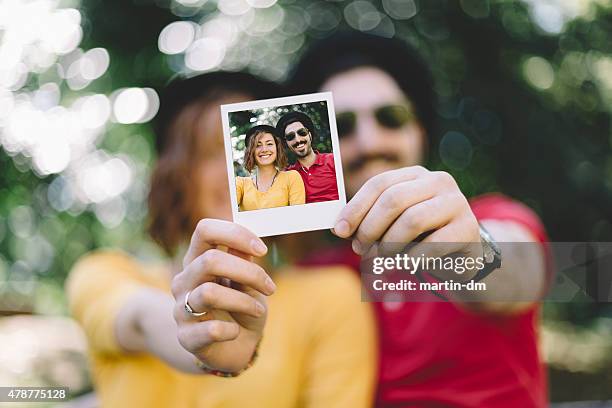eccentric couple holding instant photo - photo strip stock pictures, royalty-free photos & images