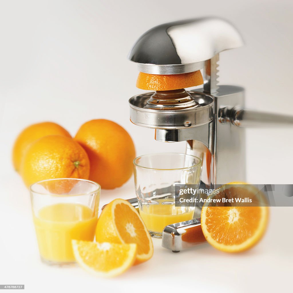 Fresh orange juice alongside an orange juicer