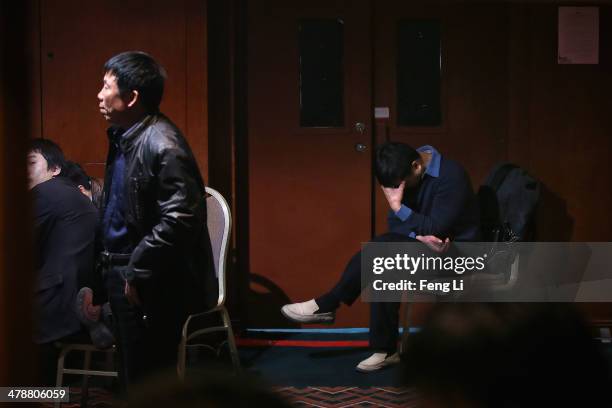 Chinese relatives of the missing passengers who were travelling onboard Malaysia Airlines flight MH370 watch a television displaying a press...