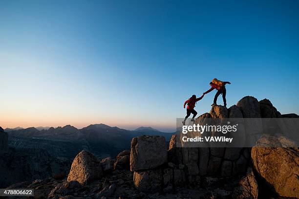 climbing to the top - climbing help stock pictures, royalty-free photos & images