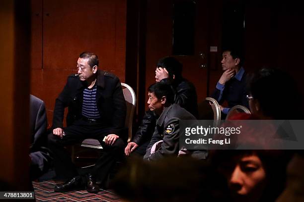 Chinese relatives of the missing passengers who were travelling onboard Malaysia Airlines flight MH370 watch a television displaying a press...