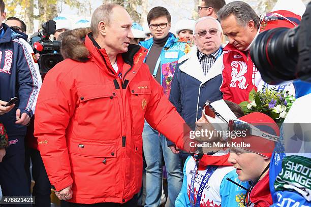 Russian President Vladimir Putin congratulates Roman Petushkov of Russia and his team after their victory in the 4 x 2.5km Open Relay cross-country...