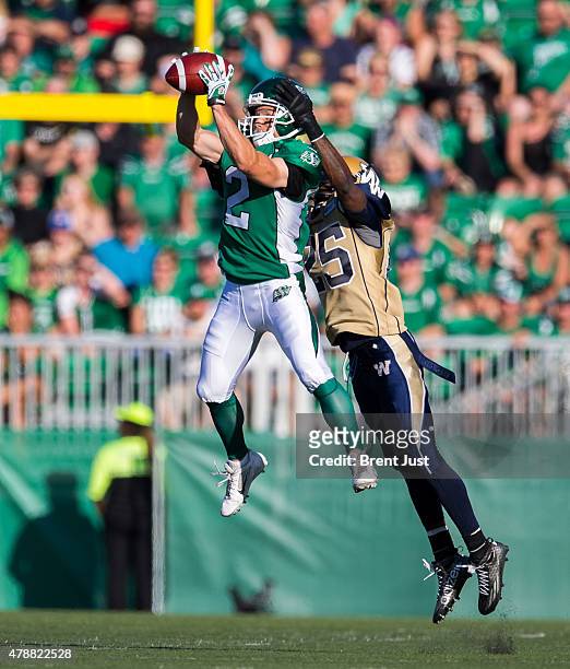 Ryan Smith of the Saskatchewan Roughriders makes a catch in front of Bruce Johnson of the Winnipeg Blue Bombers in first half action in a game...