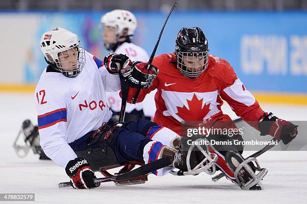 Tyler McGregor of Canada is challenged by Magnus Bogle of Norway during the ice sledge hockey bronze medal game between Canada and Norway at the...