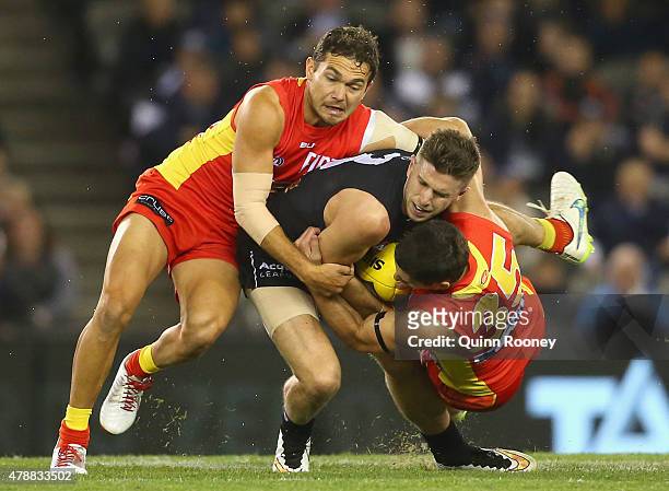 Marc Murphy of the Blues is tackled by Jarrod Harbrow and Michael Rischitelli of the Suns during the round 13 AFL match between the Carlton Blues and...