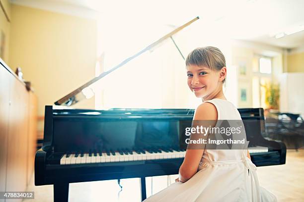 little girl playing on grand piano - pianist stock pictures, royalty-free photos & images