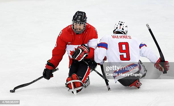 Billy Bridges of Canada avoids the tackle of Morten Vaernes of Norway during the Ice Sledge Hockey Bronze Medal match between Canada and Norway at...