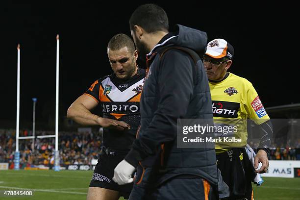 Robbie Farah of the Wests Tigers looksat his injured hand as he speaks to the trainer during the round 16 NRL match between the Wests Tigers and the...