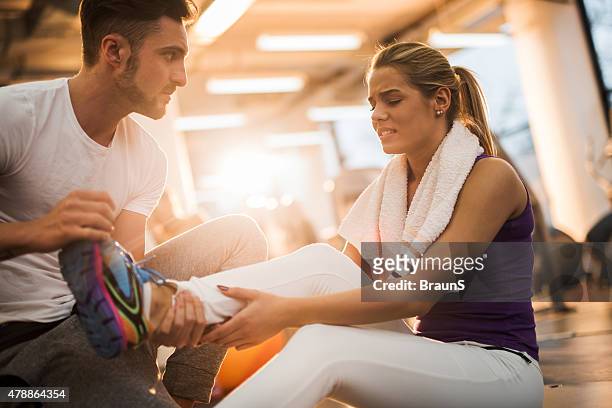 fitness instructor assisting young woman who had injured herself. - sports injury stock pictures, royalty-free photos & images