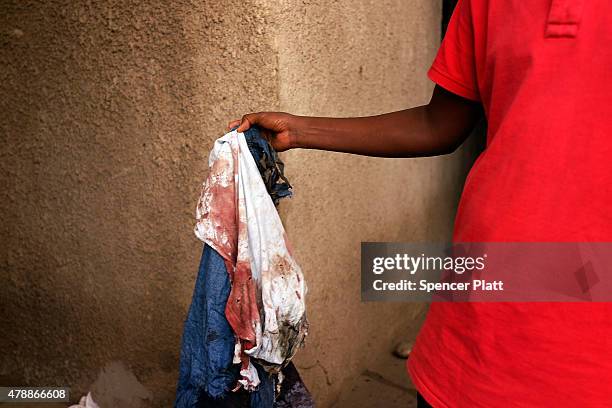 The bloody clothes of a man who was killed by police the previous evening are held on June 28, 2015 in Bujumbura, Burundi. Patrick Ndikumana was shot...