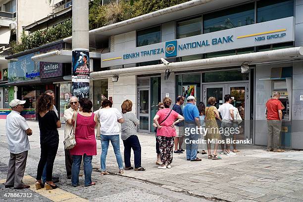 Greeks queue in front of the National Bank to use ATM to withdraw cash on June 28, 2015 in Athens, Greece. Greece is anxiously awaiting a decision by...
