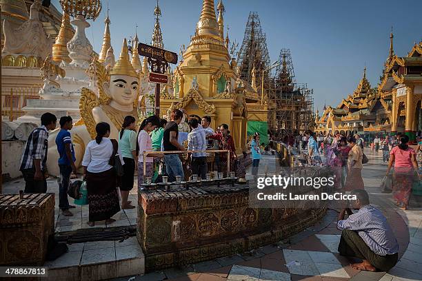 Burmese citizens partake in the washing the Buddha ritual and pray at the base of Shwedagon pagoda during the full moon festival on March 15, 2014 in...
