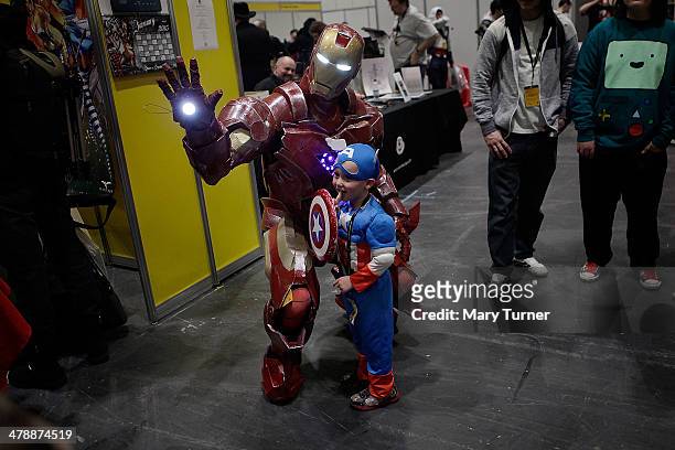 Little boy dressed as Captain America has his photograph taken with the Iron Man as they attend the London Super Comic Convention in the Excel Centre...