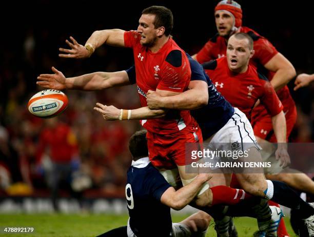 Wales flanker Sam Warburton passes the ball as he is tackled by Scotland scrum-half Greig Laidlaw during the Six Nations international rugby union...
