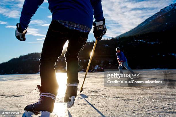 spielen eishockey auf zugefrorenen see im sonnenuntergang. - pond hockey stock-fotos und bilder