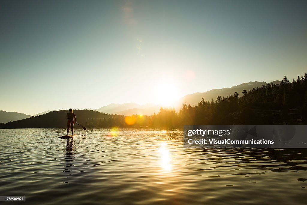 Paddleboarding on lake during sunrise or sunset.