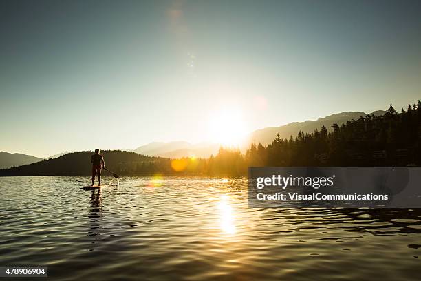 paddleboarding on lake during sunrise or sunset. - paddle board stock pictures, royalty-free photos & images