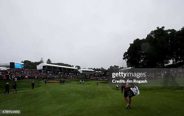 Bubba Watson, Brian Harman and Graham DeLaet of Canada walk to the 18th green during the final round of the Travelers Championship at TPC River...