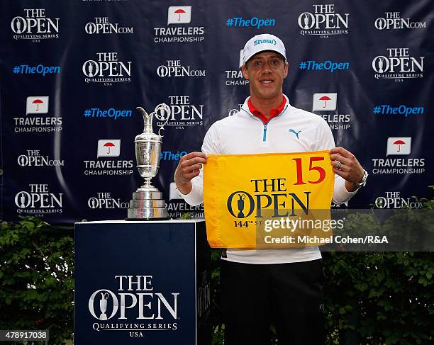 Graham DeLaet of Canada holds a hole flag and stands next to the Open Championship Trophy after qualifying for the Open Championship during the final...