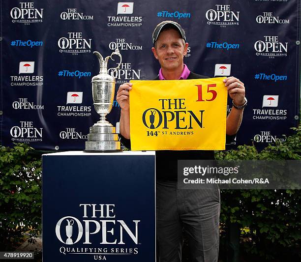 Luke Donald of England holds a hole flag and stands next to the Open Championship Trophy after qualifying for the Open Championship during the final...