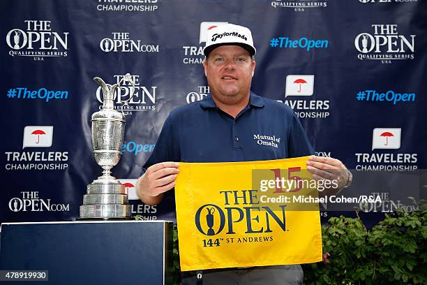 Carl Pettersson of Sweden holds a hole flag and stands next to the Open Championship Trophy after qualifying for the Open Championship during the...